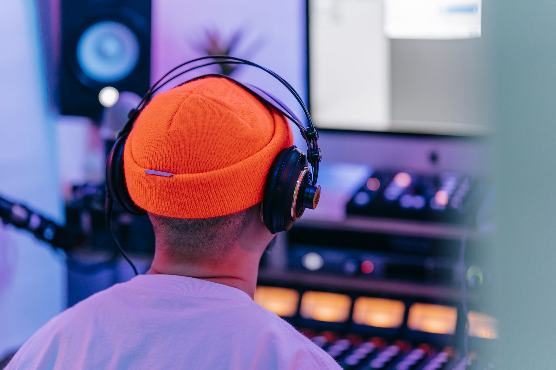 Person wearing headphones reviewing AI-generated music on a laptop in a studio